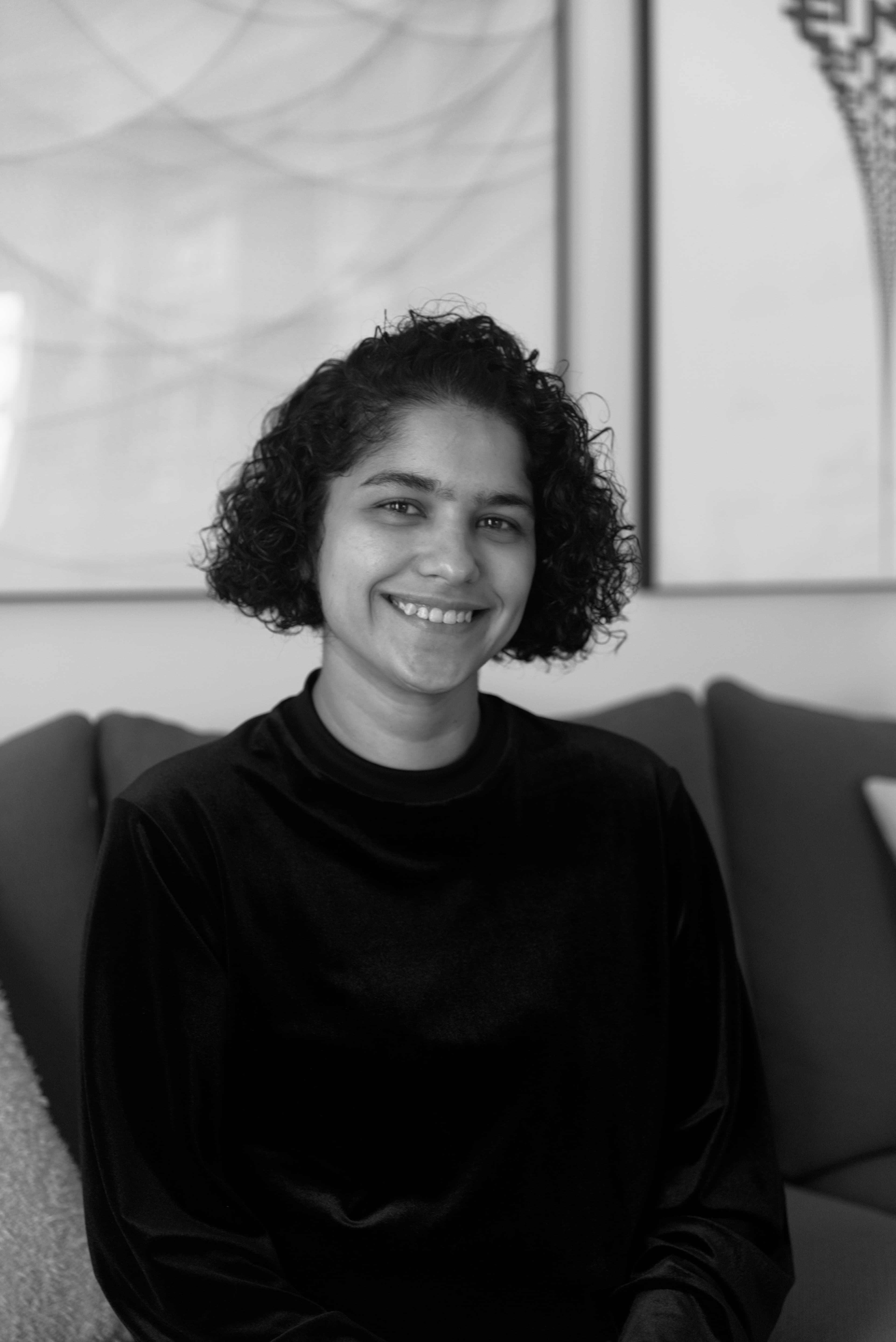Rekha smiling, seated on a couch